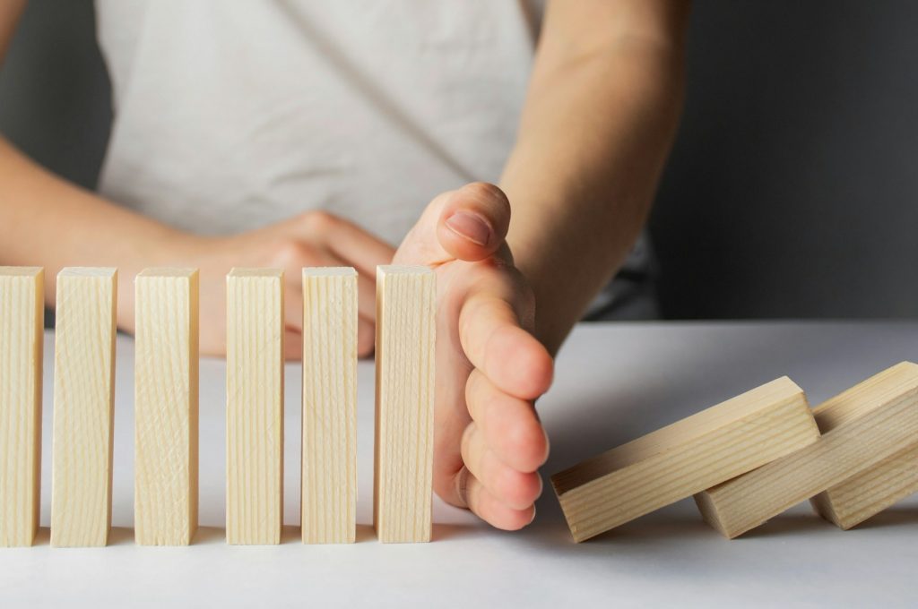 Business concept. Business destruction. Businessman stops the domino effect. Risk management.