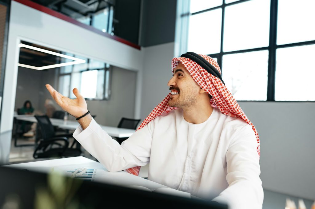 Young muslim businessman in traditional outfit working at the table in office